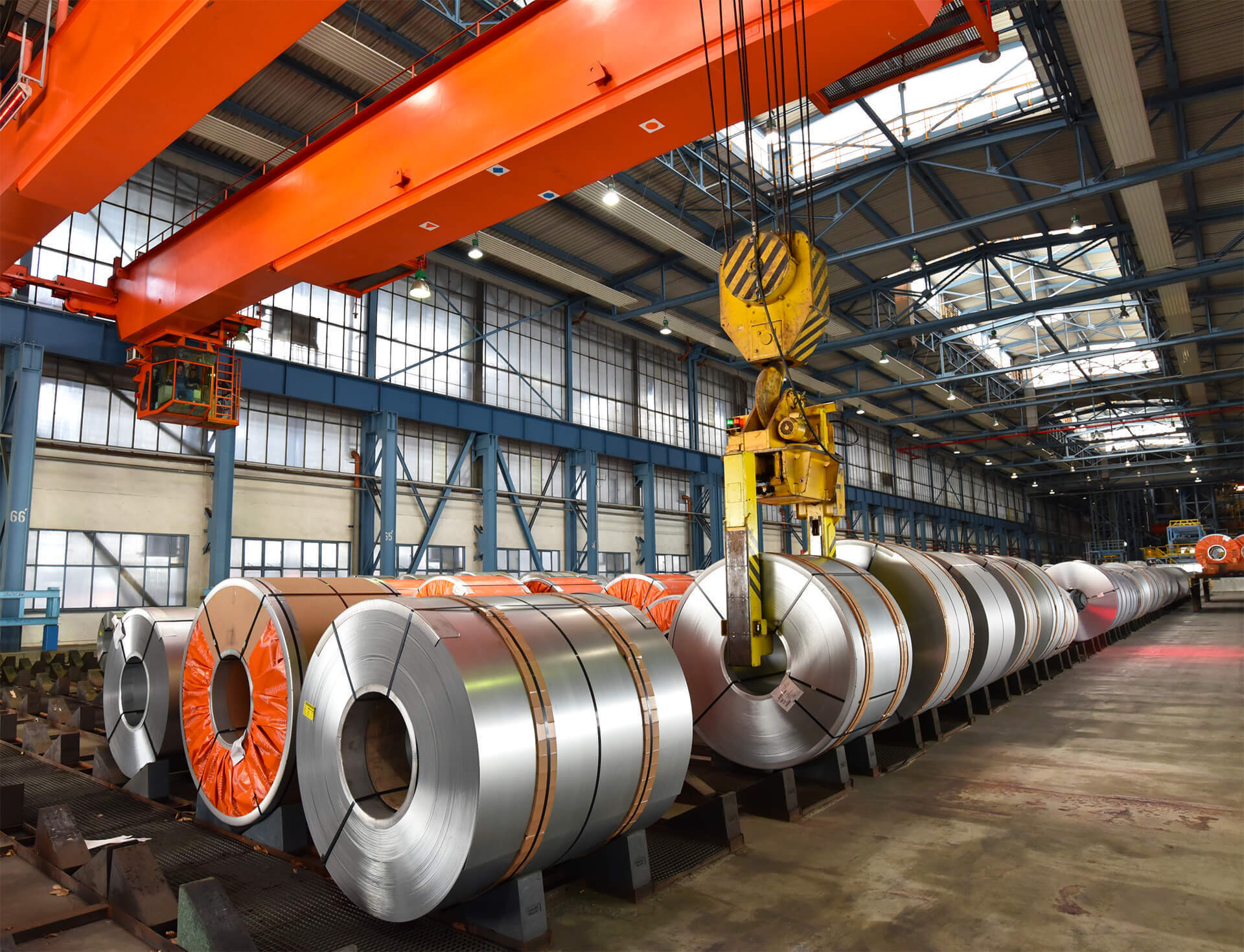 Steel coils in a factory hall beneath an overhead crane